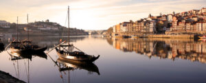 Waterfront in Porto at sunrise, with calm water and a boat in the harbour, seen in our Portuguese Camino tour | EPIcURIOUS travel